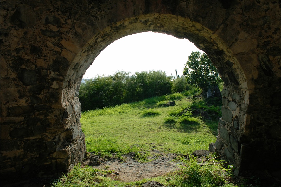 View from inside a stone mill building with an arched opening that leads to green rolling hills