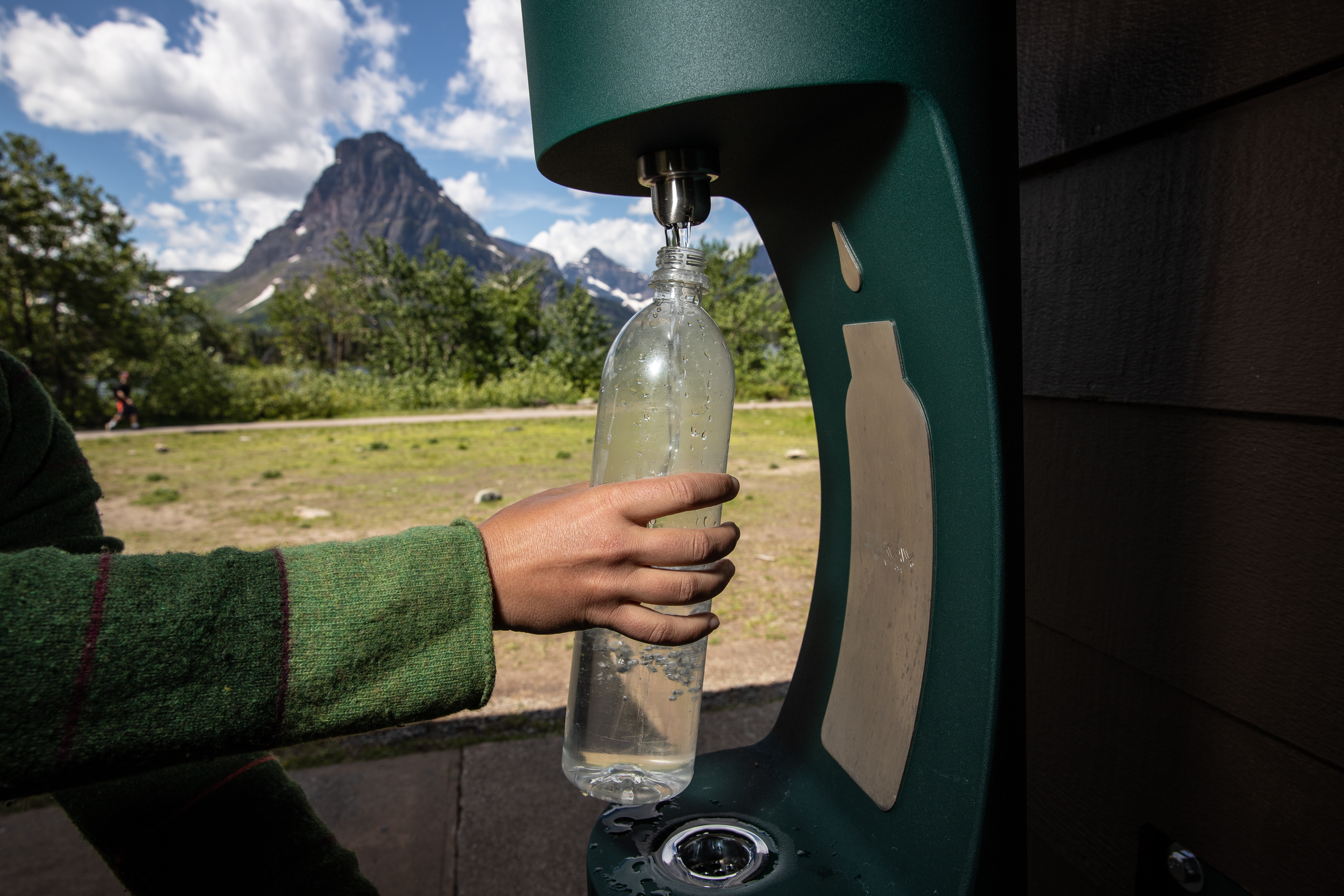 A person refills a water bottle at a water bottle refill station