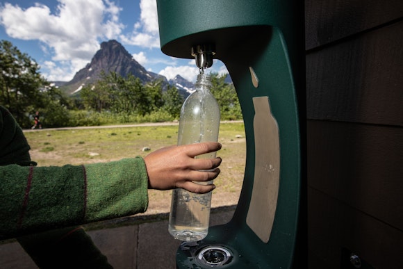A person refills a water bottle at a water bottle refill station