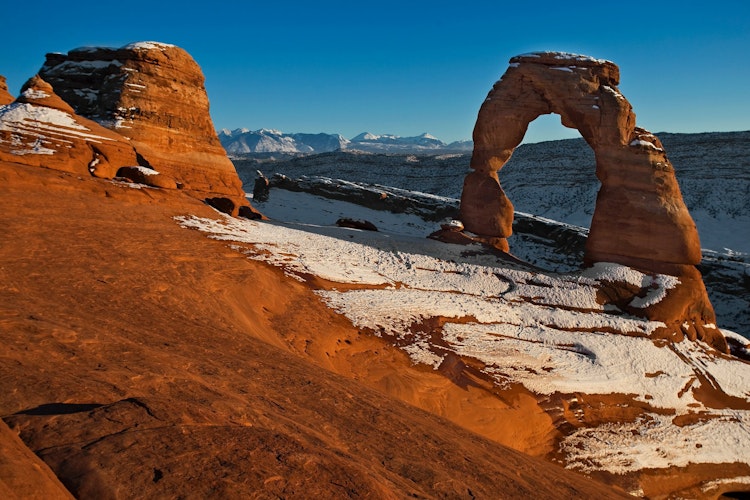 Snow dusts the red rocks and delicate arch of Arches National Park