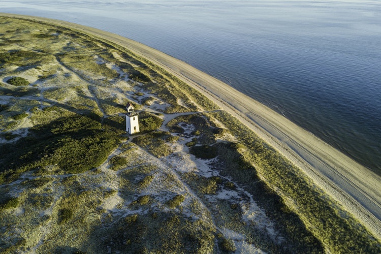 Aerial shot of lighthouse along a sandy beach