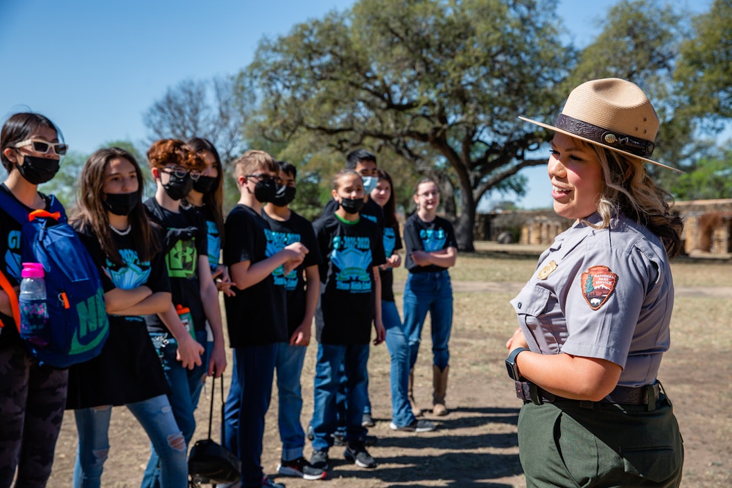 A group of students gather to listen to a park ranger