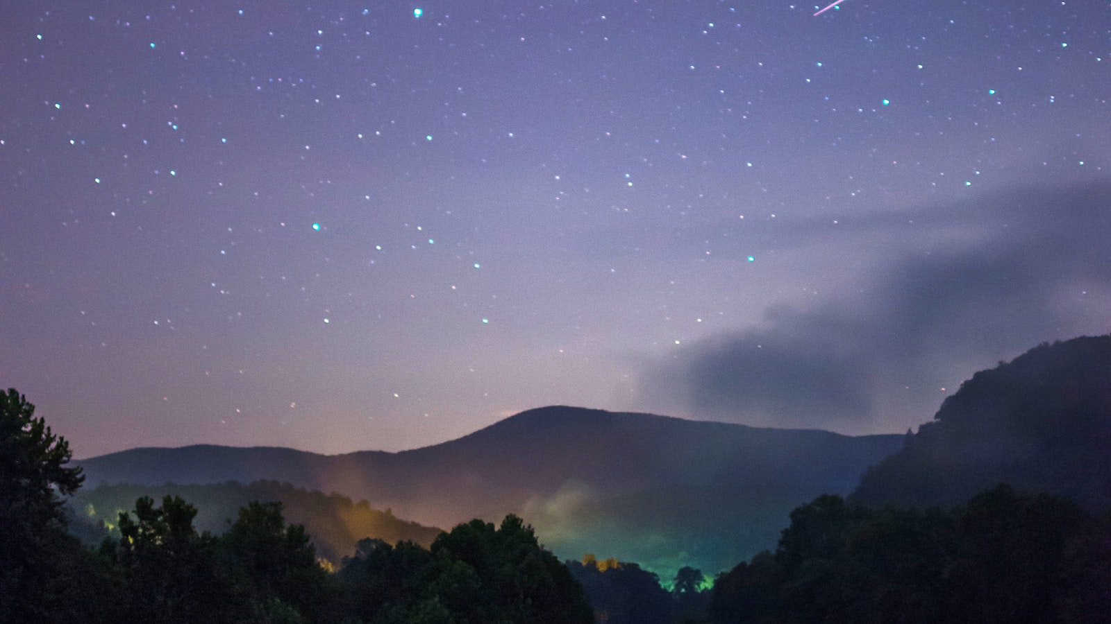 At night, stars above a mountain range