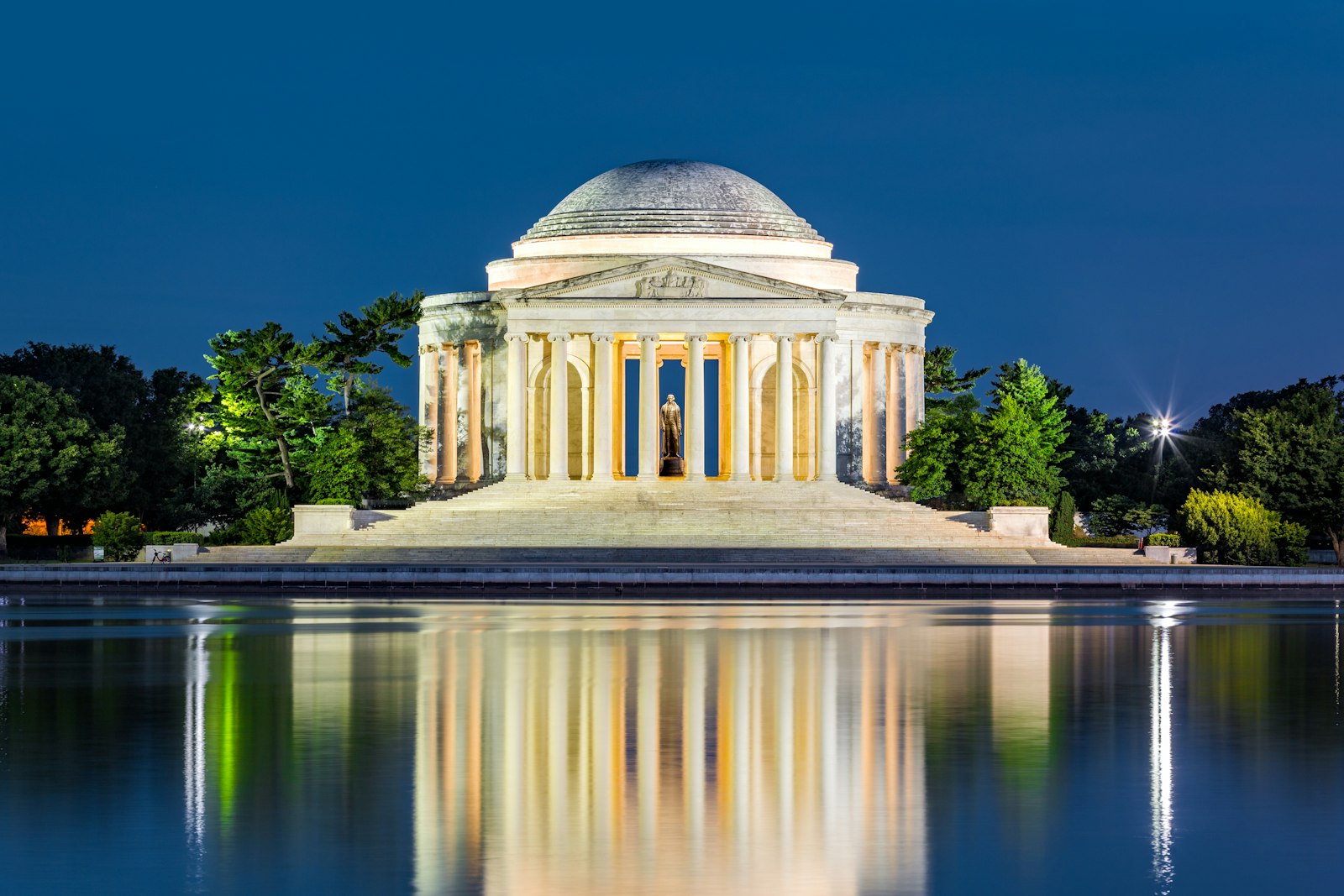 At night, a reflection of the Jefferson Memorial, illuminated, on still water