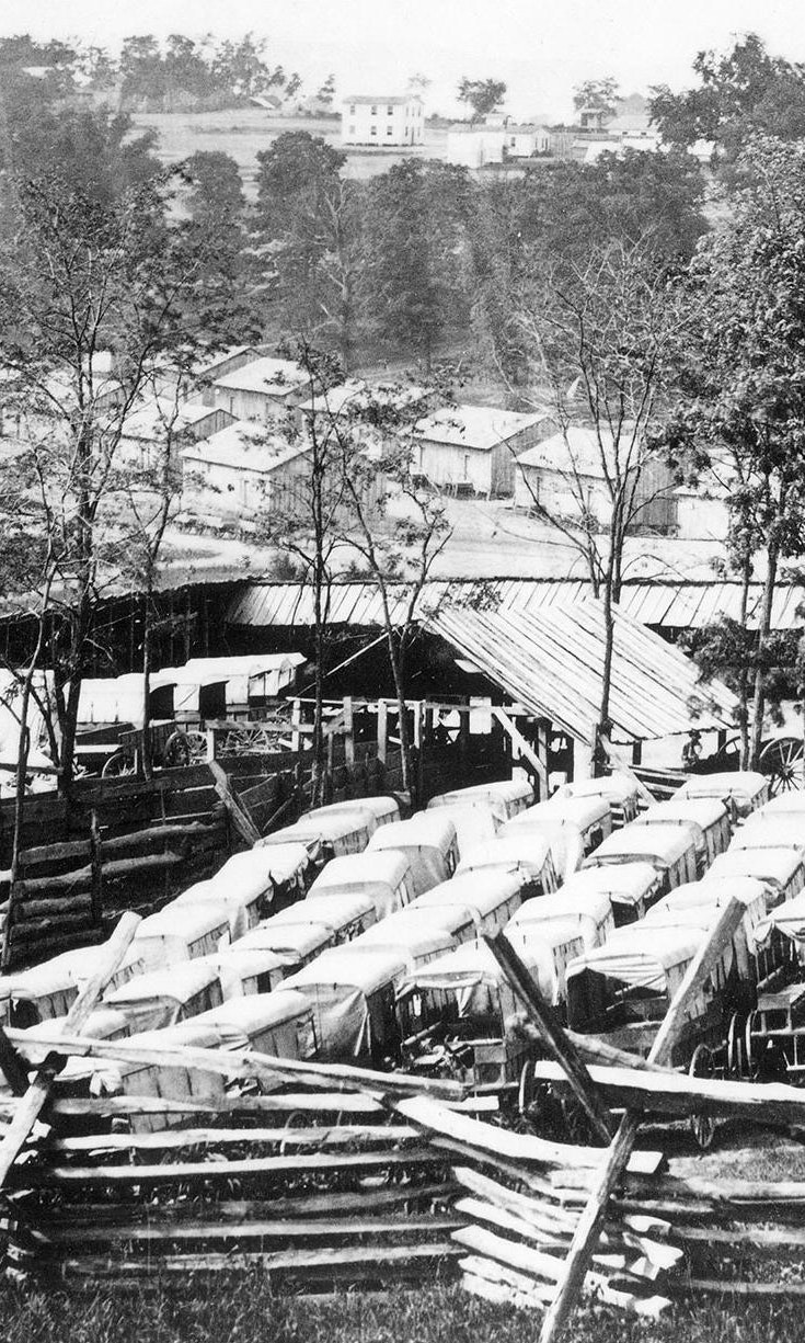 Historic black and white image of vehicles and barracks at Camp Nelson National Monument