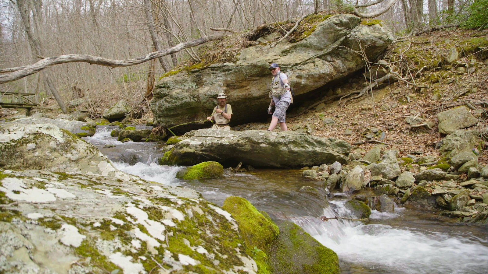 Two people stand on the side of a rocky creek