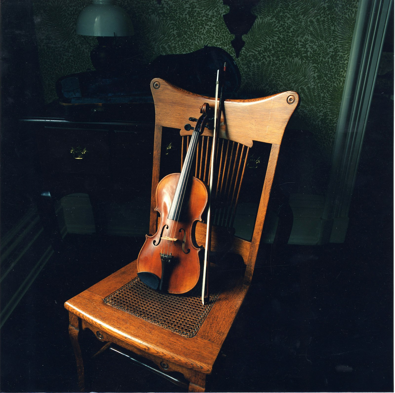 An antique violin sites atop an antique wooden chair