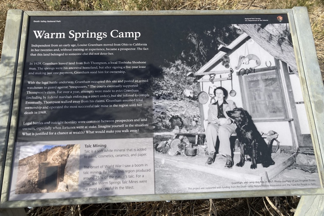 Photo of a wayside exhibit titled "Warm Springs Camp," featuring a black and white photograph of a woman and a dog