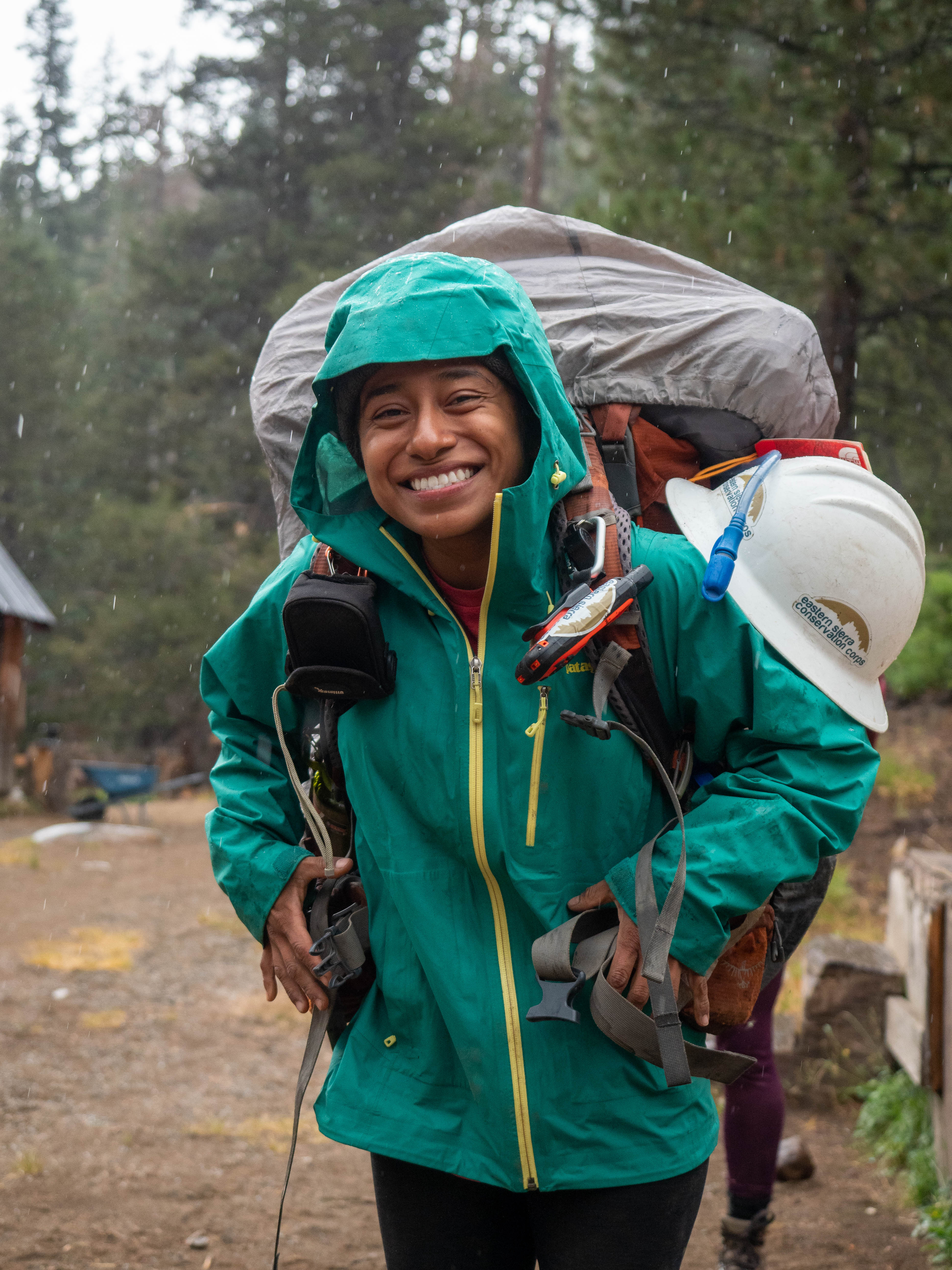 Person decked out in hiking and camping gear smiles at the camera