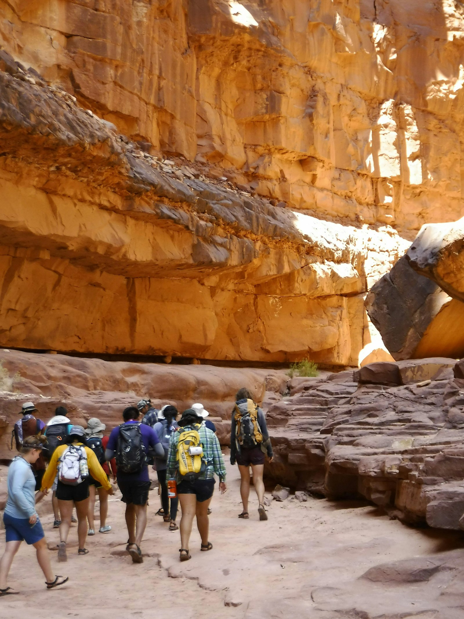 A group of people walk through the base of a canyon