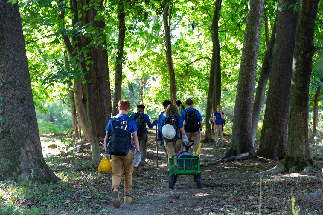 Crew, wearing matching blue shirts, walks along a trail