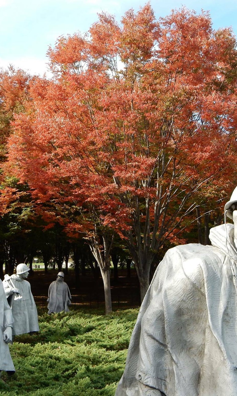 Statues of Korean War soldiers against the colors of orange autumnal leaves