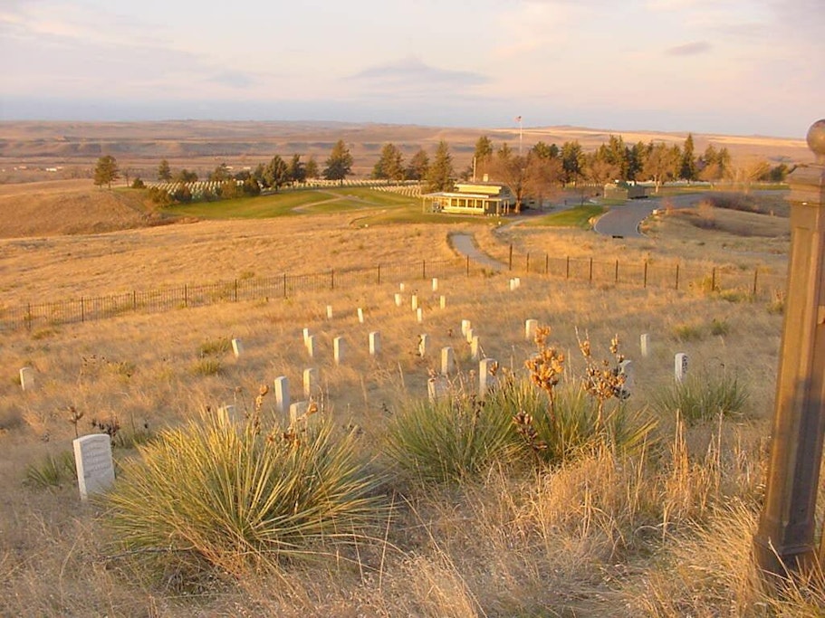 A dry, grassy plain slopes downwards toward the visitor center