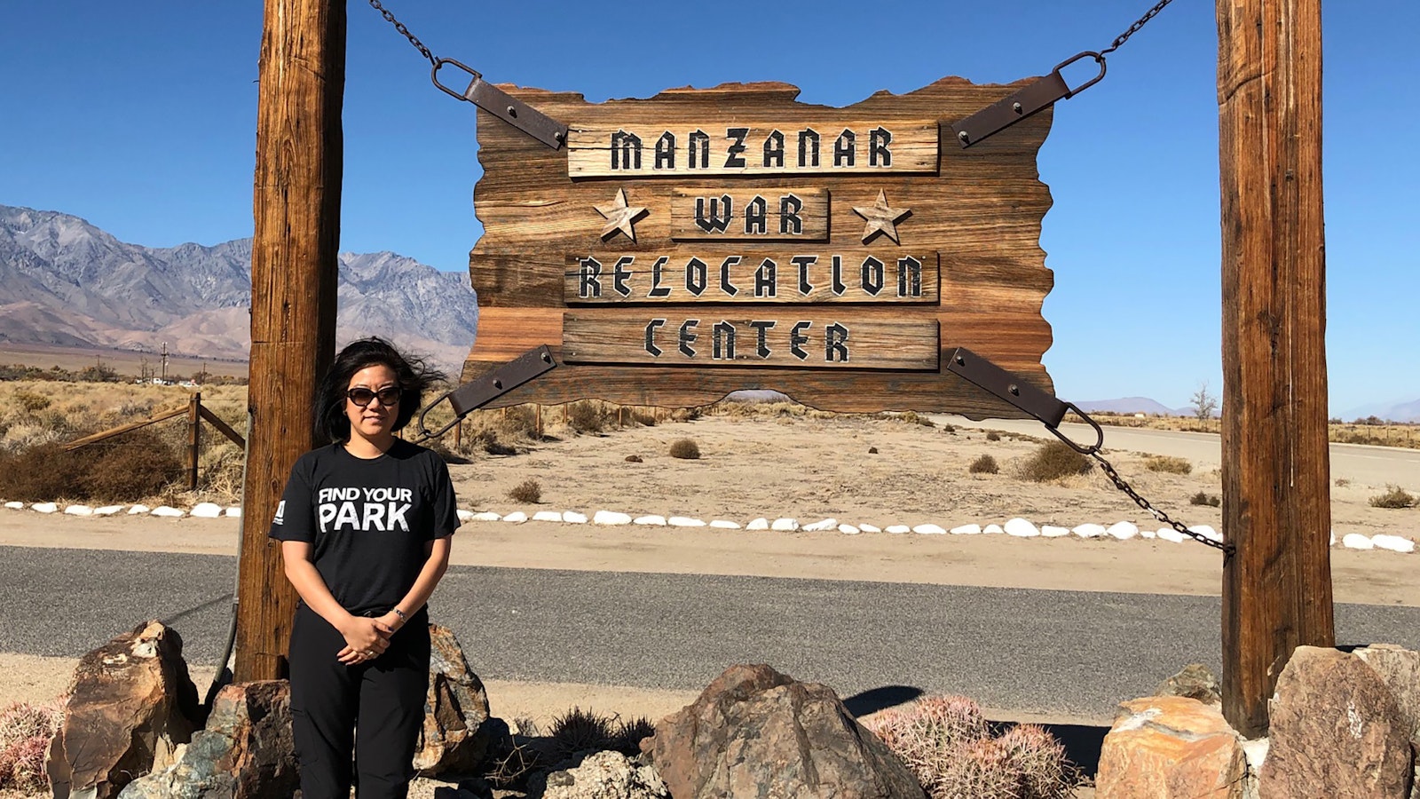 Kim stands next to a sign that reads "Manzanar War Relocation Center"