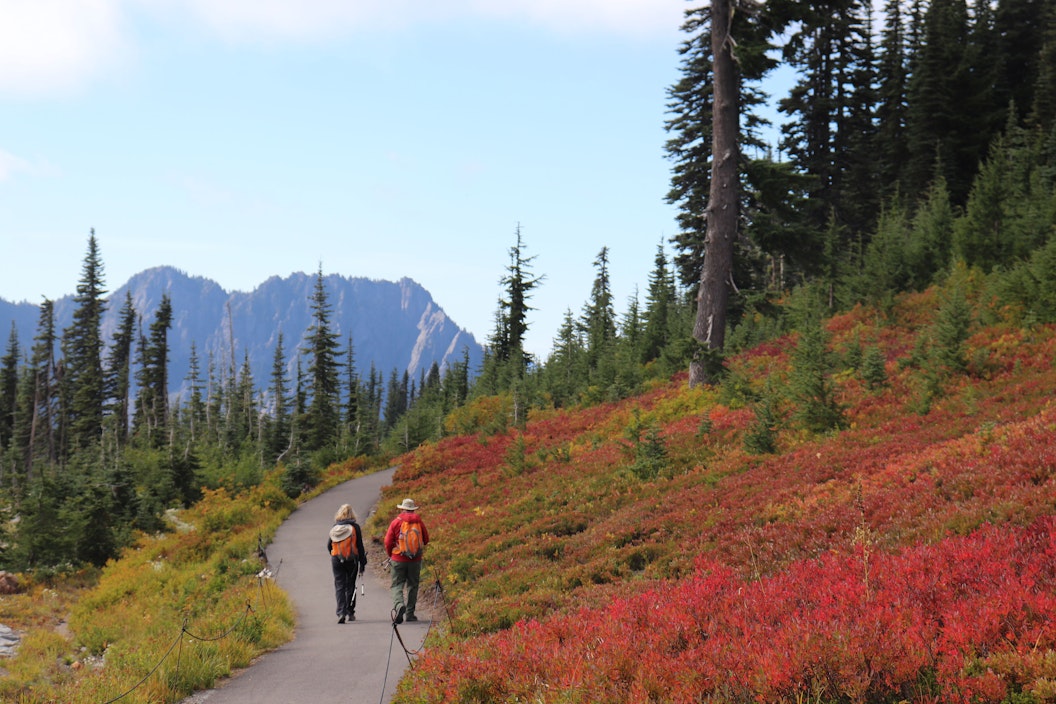 Hikers walks along a paved trail on a mountainside