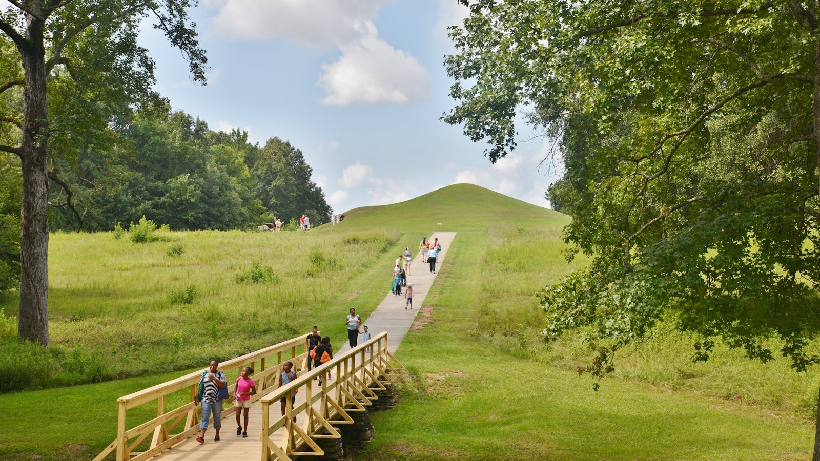 A wooden path leads upwards towards an earthern mound
