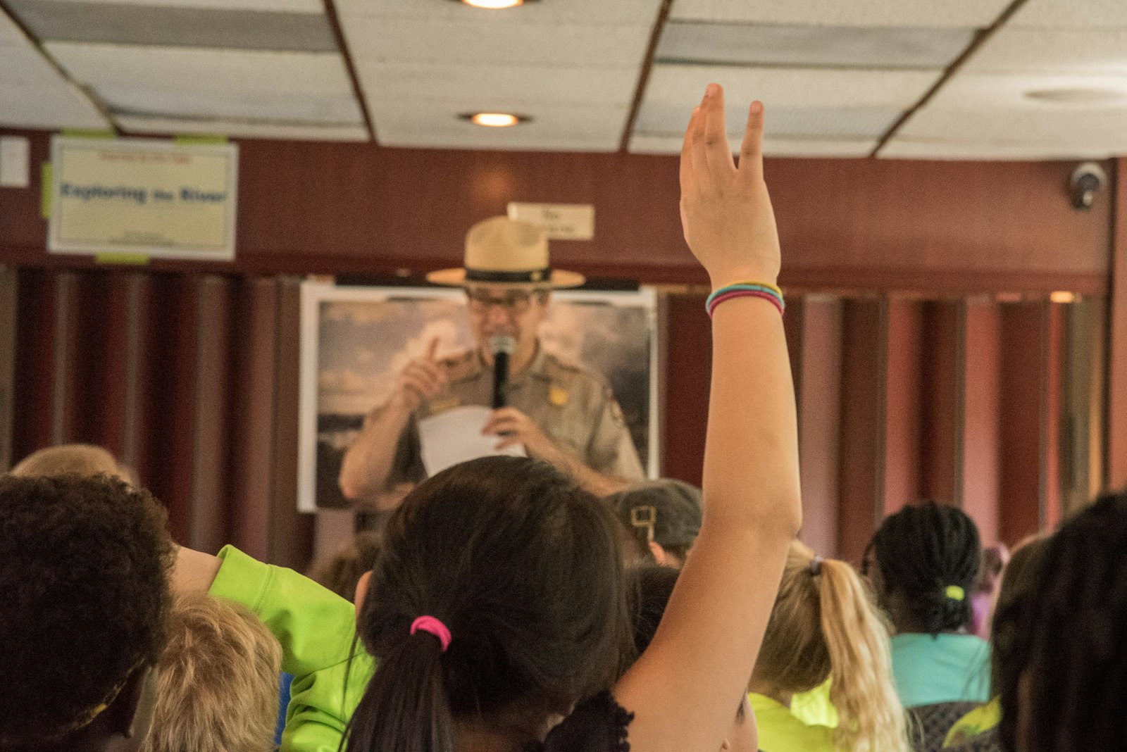 A group of students listen to a ranger speak. One raises their hand.
