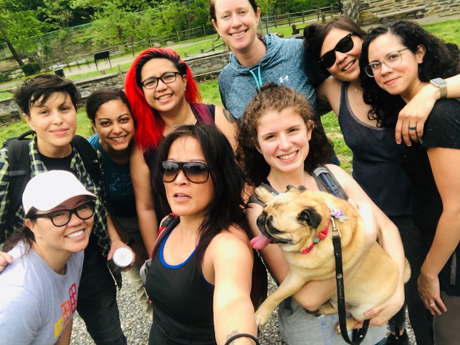 A group of people, and one pug, pose for a photo in Rock Creek Park