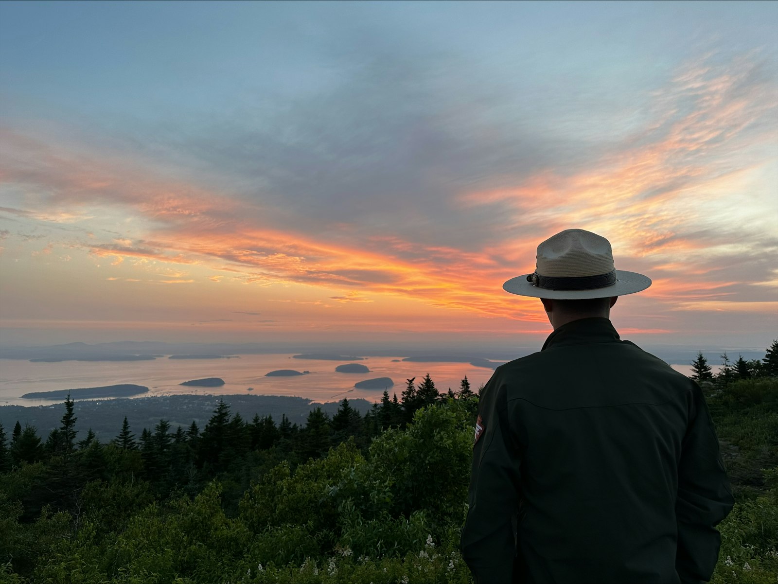 Park ranger at the top of Cadillac Mountain watches sunrise over Frenchman Bay.