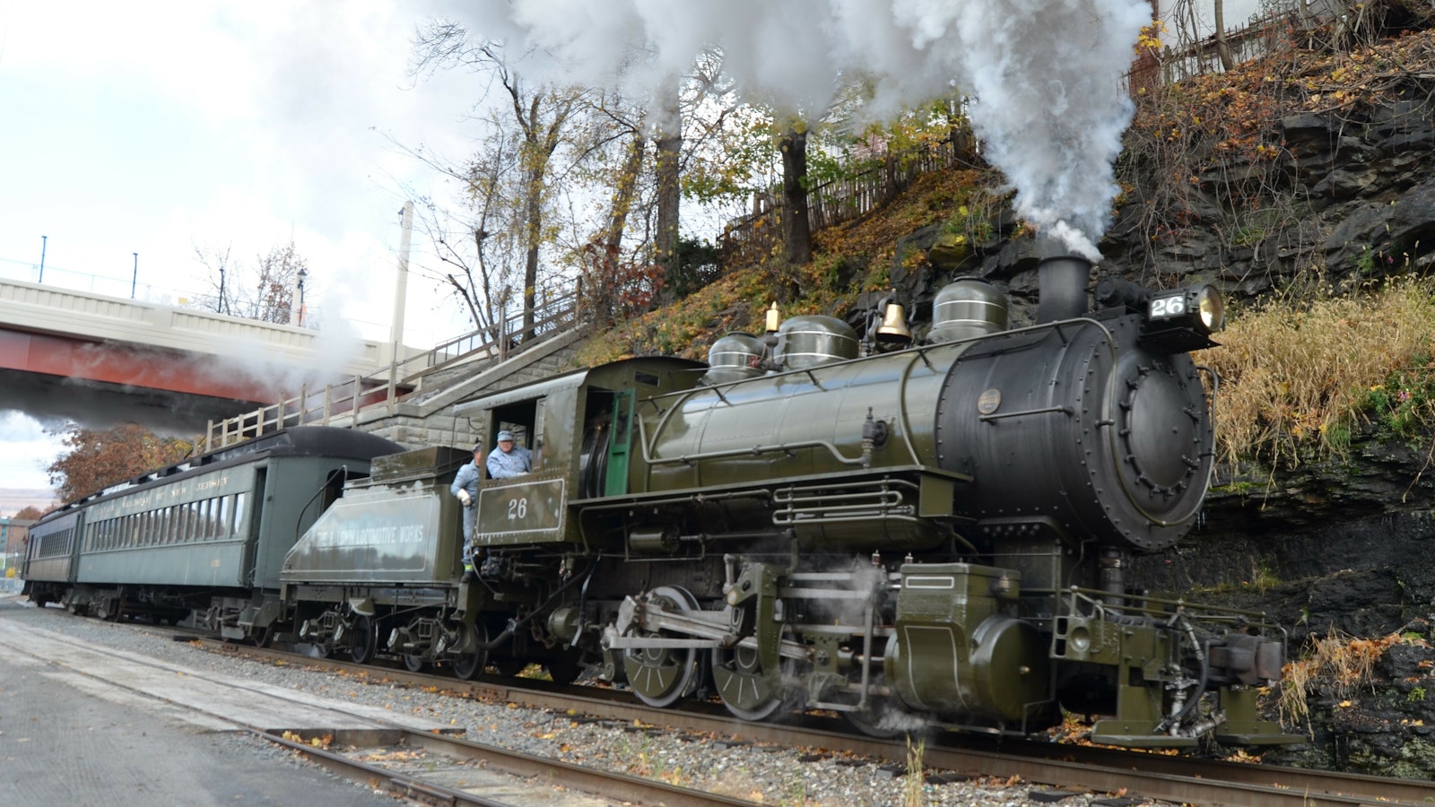 Steam train races forward along a hillside