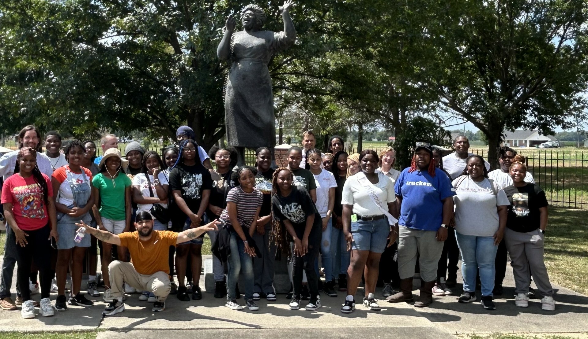 A group of people posing for a photo standing in front of a statue