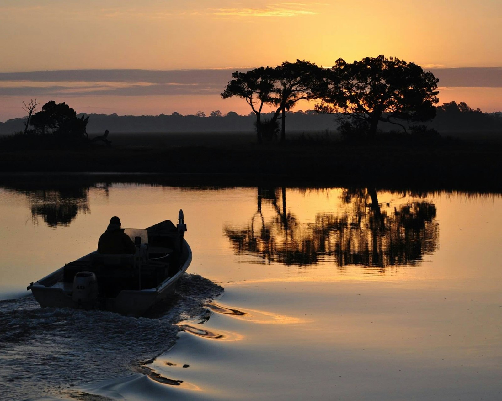 A person on a boat at sunrise at Cedar Point boat ramp at Timucuan Ecological & Historic Preserve
