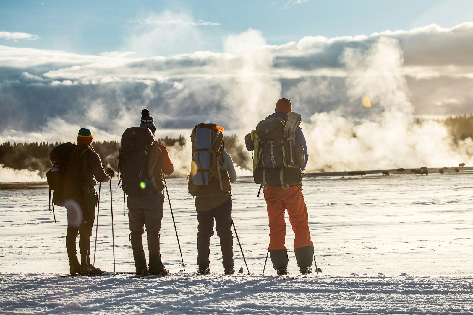 Four hikers watch a geyser in winter